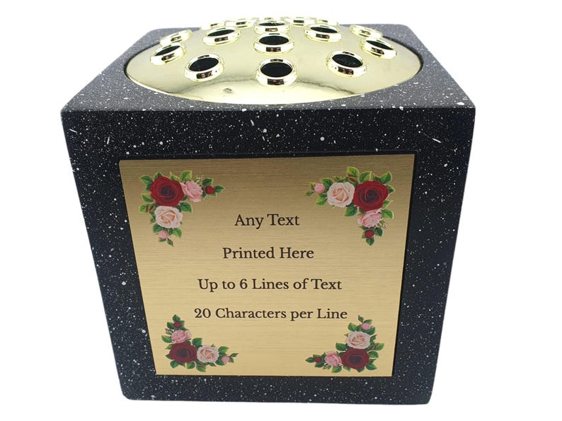 May include: Black speckled floral arrangement vase with a gold-colored top featuring multiple holes. A gold plaque on the front has text that reads "Any Text Printed Here Up to 6 Lines of Text 20 Characters per Line" with floral accents.