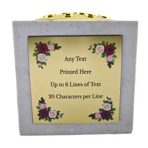 May include: A square, light gray memorial urn with a gold-colored plaque. The plaque has floral corner accents and the text "Any Text Printed Here Up to 6 Lines of Text 20 Characters per Line". The top has gold accents.