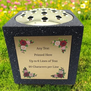 May include: Black granite memorial vase with a gold metal top and a gold plaque with a floral design. The plaque has the text "Any Text Printed Here Up to 6 Lines of Text 20 Characters per Line".