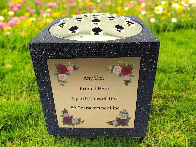 May include: Black speckled memorial flower vase with a gold-colored top and a gold plaque. The plaque has text that reads "Any Text Printed Here Up to 6 Lines of Text 20 Characters per Line". Floral accents adorn the corners.
