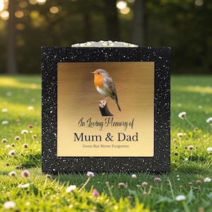 May include: A black memorial box with a gold-colored plaque featuring a robin perched on a branch. The text "In Loving Memory of Mum & Dad" and "Gone But Never Forgotten" is displayed on the plaque.