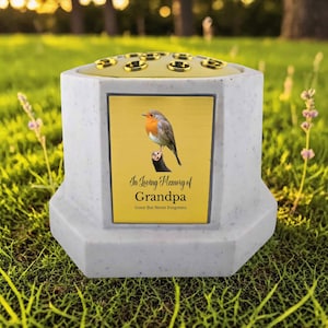 May include: A memorial vase with a robin illustration on a yellow background, inscribed with "In Loving Memory of Grandpa." The vase is light gray with a gold-colored top featuring multiple flower holders. The text "Gone But Never Forgotten" is also included.