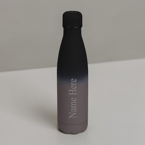 May include: A matte black water bottle with a vertical gradient fading into a muted grey at the base. The bottle features a matching black screw-top lid and the text Name Here printed in a light grey serif font vertically along the side.