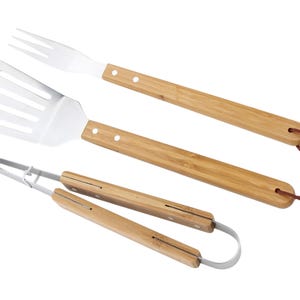 May include: A collection of three barbecue tools made from stainless steel and bamboo. The set includes a spatula, tongs, and a fork. The bamboo handles have a natural wood grain finish and are attached with small rivets. Each tool has a leather loop for hanging.