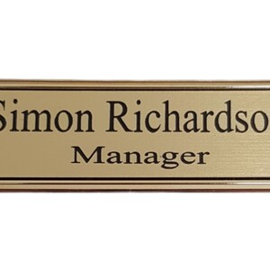 May include: Gold name tag with black text that reads "Simon Richardson Manager".