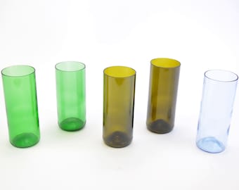 May include: Five glass drinking glasses, two green, two brown, and one blue. All the glasses are the same size and shape.