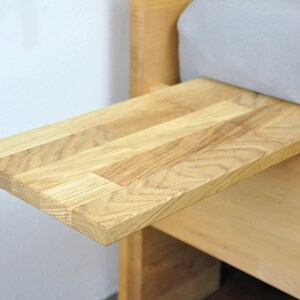May include: A wooden bedside table with a pull-out tray. The tray is made of light wood and has a natural finish.