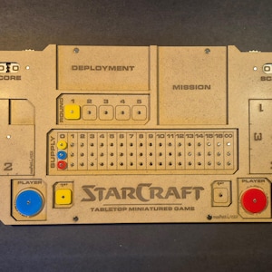 Peut inclure: Un plateau de jeu de figurines StarCraft en bois. Le plateau comporte des sections pour le score, le déploiement, la mission et les informations sur les joueurs. Il comporte des emplacements pour les marqueurs de tour et le suivi des fournitures.
