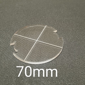 Può includere: Un cerchio di plastica trasparente con quattro linee che lo dividono in quarti. Il cerchio ha un diametro di 70 mm.