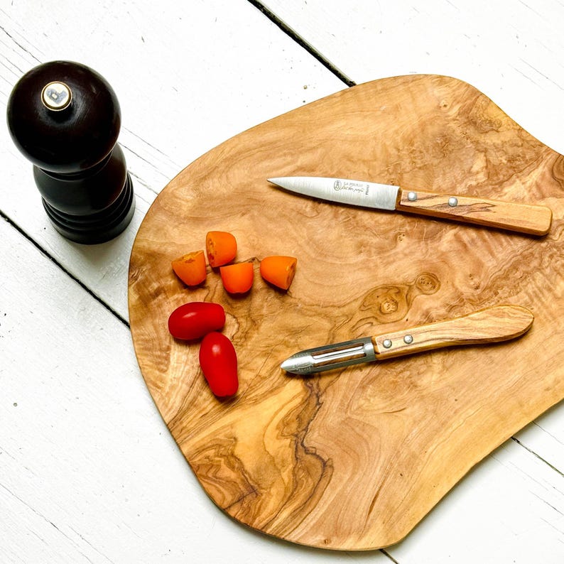 French kitchen knife and peeler knife on olive wood board