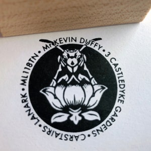 Pu&ograve; includere: Un timbro circolare in bianco e nero con un design di ape e fiore. Il testo recita "Mr. Kevin Duffy - 3 Castledyke Gardens - Carstairs - ML11 8TN."