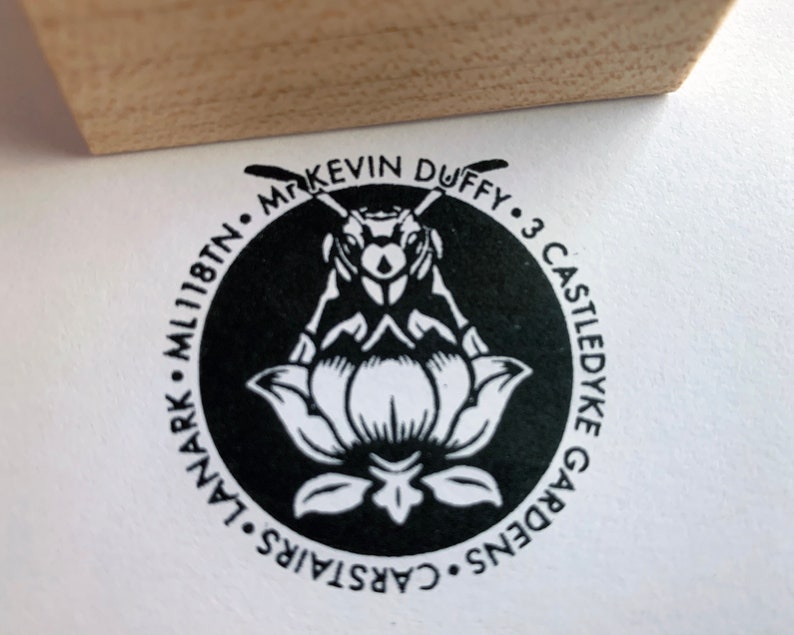 Pu&ograve; includere: Un timbro circolare in bianco e nero con un design di ape e fiore. Il testo recita "Mr. Kevin Duffy - 3 Castledyke Gardens - Carstairs - ML11 8TN."