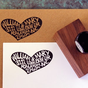 May include: A black rubber stamp with a heart-shaped design. The stamp reads "WILLIAM & MARY 3112 LONG BOW DR RALEIGH, NC 27604".