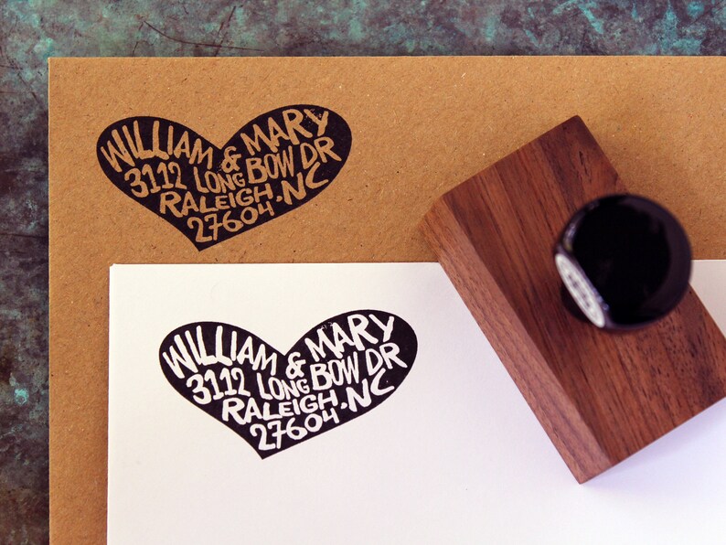 May include: A black rubber stamp with a heart-shaped design. The stamp reads "WILLIAM & MARY 3112 LONG BOW DR RALEIGH, NC 27604".