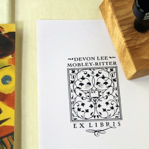 May include: Black and white bookplate stamp with a decorative design and the text "Devon Lee Mobley-Ritter Ex Libris".