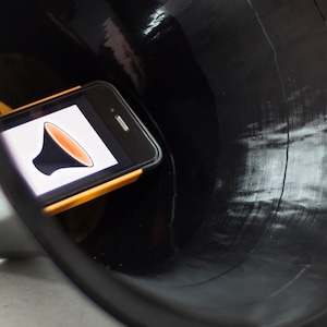 May include: A black vinyl record player with a smartphone inside. The phone screen shows a volume icon.