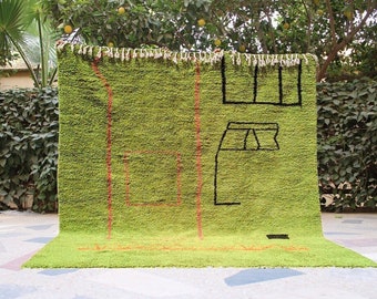 May include: A green rug with a geometric design in black and orange. The rug has a fringe border.