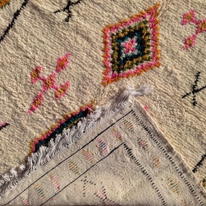 May include: A white rug with a fringe border and colorful geometric patterns in pink, blue, green, and yellow.