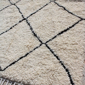 May include: White shag rug with a black diamond pattern. The rug has a fringe border.