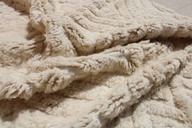 Puede incluir: Primer plano de una alfombra esponjosa de color crema con un patr&oacute;n tejido texturizado. La alfombra est&aacute; hecha de fibras naturales suaves y tiene una sensaci&oacute;n lujosa.