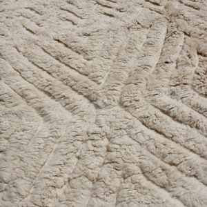 Puede incluir: Primer plano de una alfombra blanca y esponjosa con un patr&oacute;n texturizado en forma de diamante. La alfombra es suave y mullida y es perfecta para a&ntilde;adir un toque de lujo a cualquier habitaci&oacute;n.