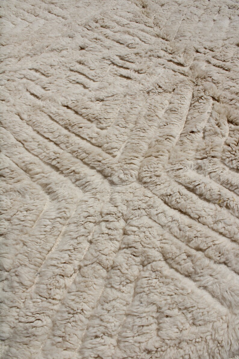 Puede incluir: Primer plano de una alfombra blanca y esponjosa con un patr&oacute;n texturizado en forma de diamante. La alfombra es suave y mullida y es perfecta para a&ntilde;adir un toque de lujo a cualquier habitaci&oacute;n.