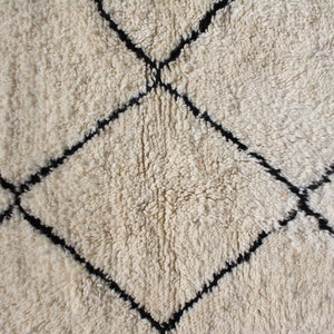 May include: A white rug with a black diamond pattern. The rug is made of a soft, fluffy material.