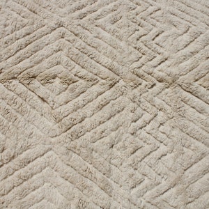 Puede incluir: Primer plano de una alfombra beige con un patr&oacute;n de diamantes. La alfombra est&aacute; hecha de un material suave y esponjoso.