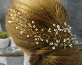 May include: A gold hair comb with crystal beads in a vine design. The comb is worn in a woman's hair.