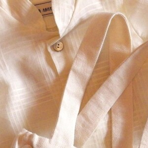 May include: A white linen shirt with a button closure and a white linen overall with straps. The text "Ensemble Shirt et chemise noire" is visible on the overall.