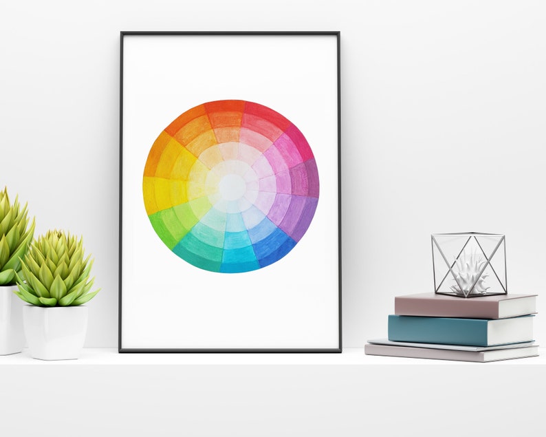 May include: A framed print of a watercolor color wheel with a white background. The color wheel is a circle with a white center and is divided into 12 sections, each a different color of the rainbow.