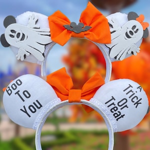 May include: White mouse ears with a white ghost and orange bow on one ear and the text "Boo To You" on the other ear. The other ear has a white ghost and orange bow and the text "A Trick Or Treat" on the other ear.