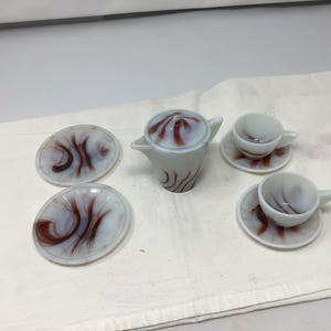 May include: A vintage white and brown swirl glass tea set with a teapot, two cups, and two saucers.