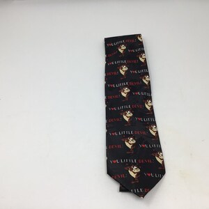 May include: A black silk tie with a repeating pattern of a cartoon Tasmanian Devil and the text "You Little Devil!" in red and white.