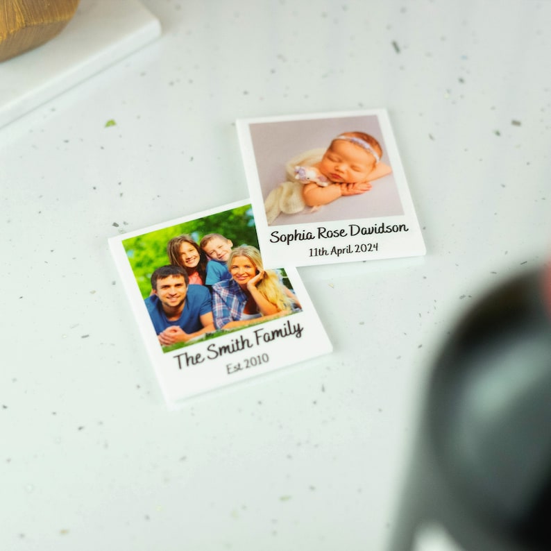 May include: Two white photo cards with images and text. The top card shows a baby girl sleeping and the text "Sophia Rose Davidson 11th April 2024". The bottom card shows a family of four smiling and the text "The Smith Family Est 2010".