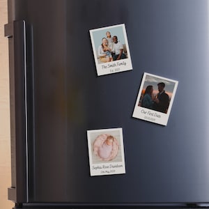 May include: Three Polaroid-style photo magnets with white borders and black text. The top magnet shows a family of four, the middle magnet shows a couple, and the bottom magnet shows a baby. The text on the magnets reads "The Smith Family Est. 2013", "Our First Date 03.10.2014", and "Sophia Rose Davidson 11th May 2024".