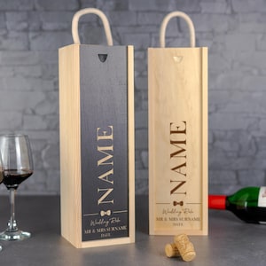 May include: Two wooden wine boxes with rope handles. One box has a dark gray front panel, the other is natural wood. Both boxes are engraved with the word "NAME" and "Wedding Role" details.
