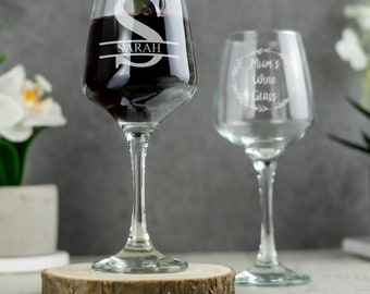 Op de afbeelding: Twee wijnglazen, waarvan er één gevuld is met rode wijn. Het glas links is gegraveerd met de letter "S" en de naam "SARAH". Het glas rechts is gegraveerd met de tekst "Mams wijnglas".