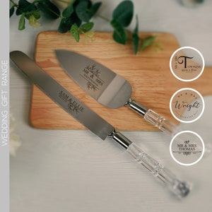Può includere: Un set di due coltelli per torta d'argento con manici trasparenti. I coltelli sono incisi con i nomi "Sam & Ellie" e "Mr. & Mrs. Whittingham".