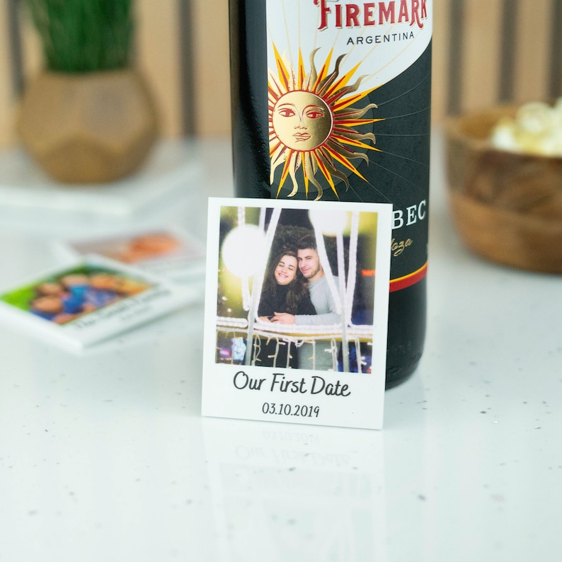 May include: A white photo card with a picture of a couple in a Ferris wheel. The text "Our First Date 03.10.2019" is printed below the photo.