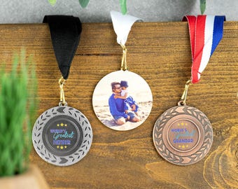 Peut inclure: Trois médailles d'or avec des rubans noir, blanc et rouge. Les médailles ont une finition argent, or et bronze. La médaille d'argent porte l'inscription "World's Greatest Father". La médaille d'or a une photo d'un homme et d'un enfant. La médaille de bronze porte l'inscription "World's Greatest Grandad".