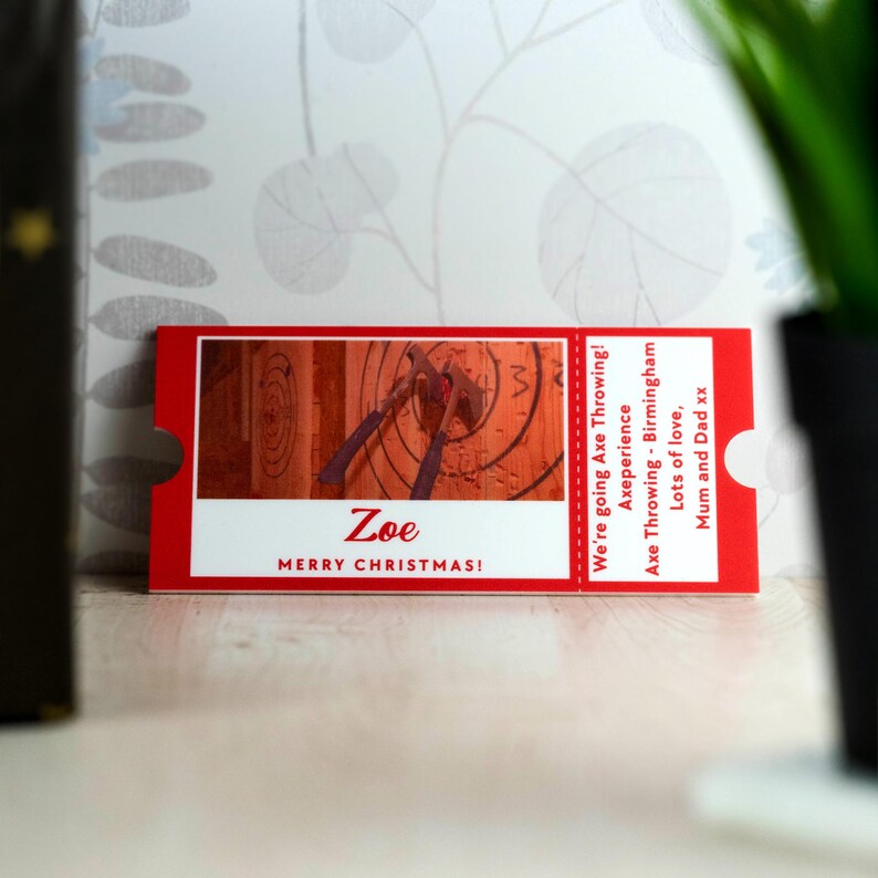 May include: Red and white gift certificate for an axe throwing experience. The certificate says "We're going Axe Throwing!" and "Axeperience Axe Throwing - Birmingham". It also says "Zoe Merry Christmas!" and "Lots of love, Mum and Dad xx".