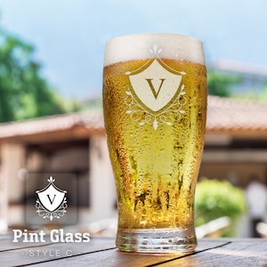Op de afbeelding: Een bevroren pintglas met een heldere vloeistof erin. Het glas heeft een decoratief ontwerp dat in de zijkant is ge&euml;tst, met een schild met de letter "V" erin. Het glas staat op een houten oppervlak.