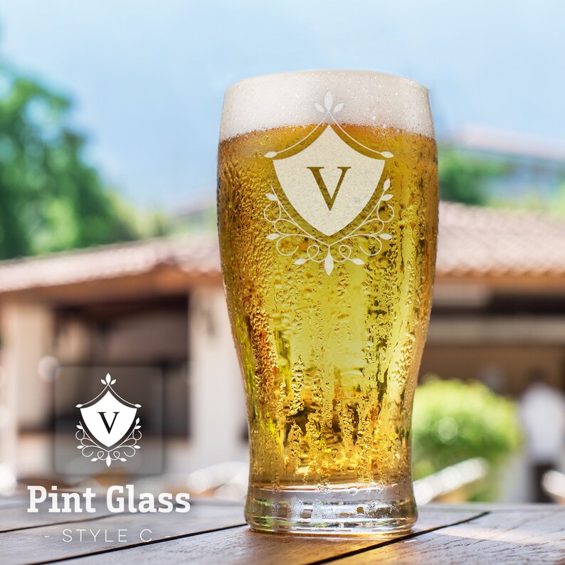 Op de afbeelding: Een bevroren pintglas met een heldere vloeistof erin. Het glas heeft een decoratief ontwerp dat in de zijkant is ge&euml;tst, met een schild met de letter "V" erin. Het glas staat op een houten oppervlak.