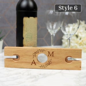 May include: Wooden wine bottle and glass holder with two slots for glasses. The holder is engraved with the letters "A" and "M" in a wreath design. The text "Style 6" is visible in the top right corner of the image.