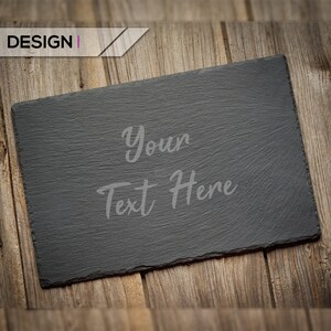 May include: A black slate serving board with a rough texture, resting on a wooden surface. The text "Your Text Here" is written in gray on the board.