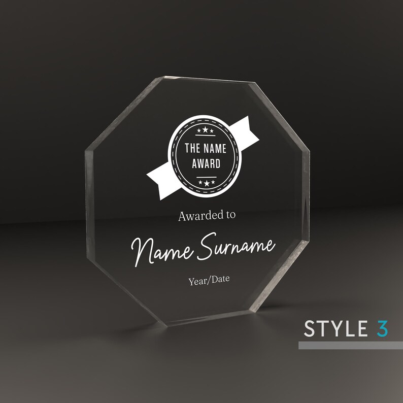 May include: A clear octagonal acrylic award plaque with a white star-shaped seal that reads "The Name Award". The plaque has the text "Awarded to Name Surname" and "Year/Date" below the seal.