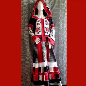 May include: A red, black, and white hooded cardigan with floral embroidery and a matching skirt. The skirt is made of different fabrics and has a layered design.