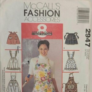 May include: McCall's Fashion Accessories sewing pattern with eight apron designs. The cover shows a woman wearing a floral apron. The aprons include various styles, such as a bib apron, a half apron, and an apron with pockets.