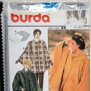 Könnte beinhalten: Ein Burda-Schnittmusterpaket mit Illustrationen von Capes in verschiedenen Stilen. Das Paket enthält Bilder eines braunen karierten Capes, eines grünen Capes und eines senffarbenen Capes. Der Text "THE NEW burda" ist sichtbar.